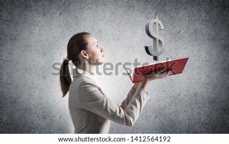 Businesswoman with dollar sign above opened notebook. Investment and money saving services. Elegant young woman in white business suit on background of grey wall. Financial company advertising.