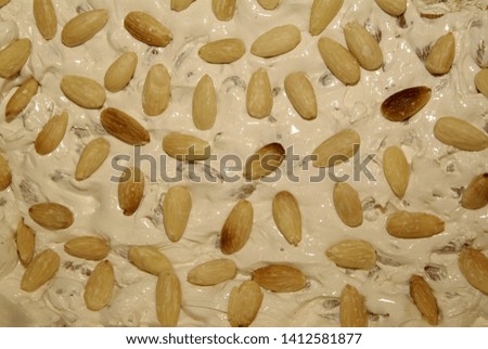 Italian torrone or nougat with almonds on a white wooden table, close up with selected focus, close up
