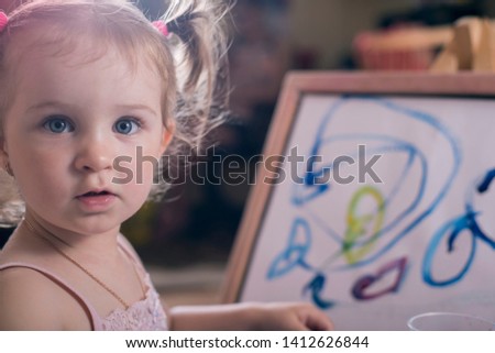 portrait of a little girl, close-up, with astonished expression of emotions, painting with colorful paints on canvas