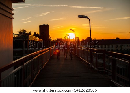 Family with a Bicycle go on the bridge against the setting sun