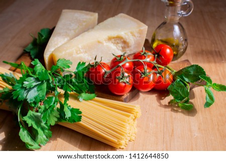 spaghetti with cheese, cherry tomatoes and mint. ingredients for pasta. spaghetti on wooden background. copy space