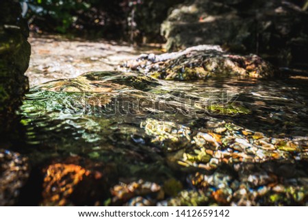 Stream of natural water source at its starting point among rocks in summer