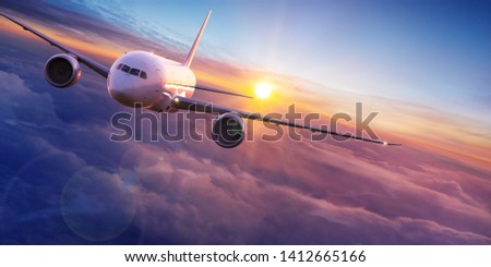 Commercial airplane jetliner flying above dramatic clouds in beautiful sunset light. Travel concept. Royalty-Free Stock Photo #1412665166