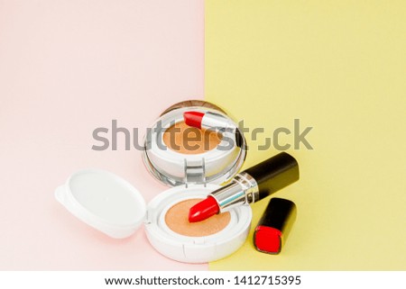 Make up products spilling on to a bright yellow and pink background with copy space, minimal style