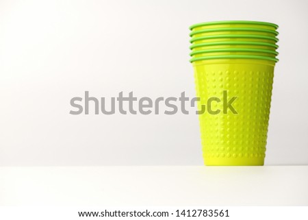 Many plastic disposable cups of green color are on the right on a white background.