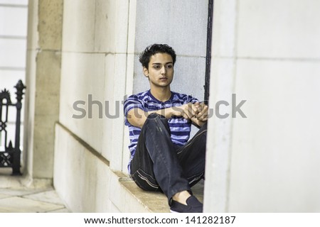 Dressing in a blue lines T shirt and  black pants, a young asian teenager is sitting on a window and into deeply thinking/Thinking Outside 