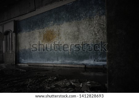 painted flag of argentina on the dirty old wall in an abandoned ruined house. concept
