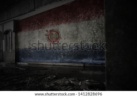 painted flag of paraguay on the dirty old wall in an abandoned ruined house. concept
