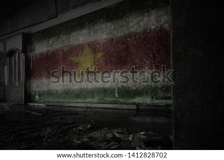 painted flag of suriname on the dirty old wall in an abandoned ruined house. concept