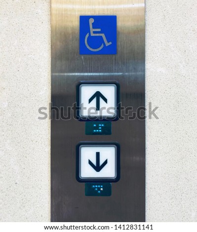 Elevator buttons with Braille codes and handicap sign. Allow signs for up and down. 