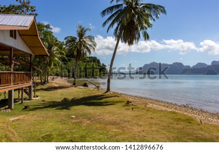 Wooden hut on tropical beach with palms and isles on background. Oriental house in beautiful lagoon. Summer vacation. Asian travel. Resort concept. Calm place for relax. Exotic leisure concept.