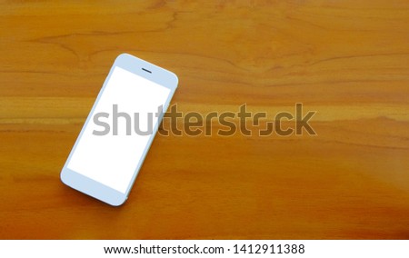 Smartphone with blank screen on wooden table background.