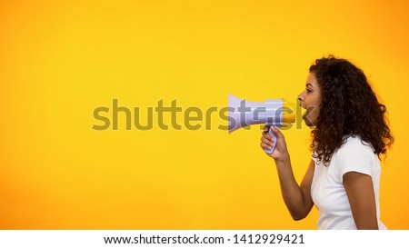 Afro-American girl screaming in megaphone, spreading information, awareness Royalty-Free Stock Photo #1412929421