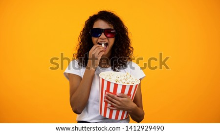 Afro-American female in 3d glasses eating popcorn and watching comedy show