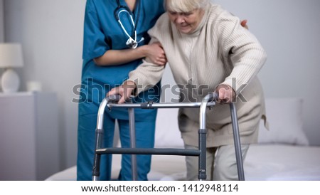 Nurse assisting patient walking frame, hip joint replacement rehabilitation Royalty-Free Stock Photo #1412948114