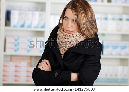 Sick woman in the pharmacy wearing a thick winter scarf and coughing while grimacing in pain Royalty-Free Stock Photo #141295009