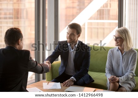 Satisfied businessmen handshake closing deal after successful office negotiations in office, happy confident male business partners shake hands signing contract at briefing. Cooperation concept