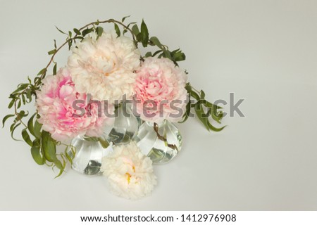 Three Small Round Glass Vases with Peonies of Various Shades of Pink and Willow Branches on a Light Background Seen From Above