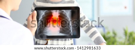 Female medic examining little girl with ultra modern scanning tablet pc showing pulmonology problems closeup