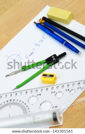 Arrangement School Supplies with Writing Geometrical Formula on White Paper  on Wooden School Desk
