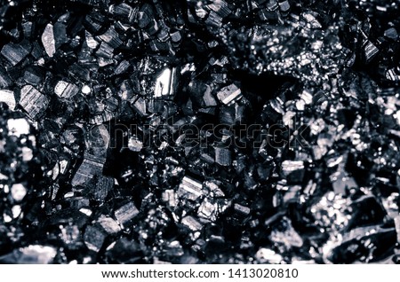 Beautiful texture of fossil dark glitter stone mineral, black background.