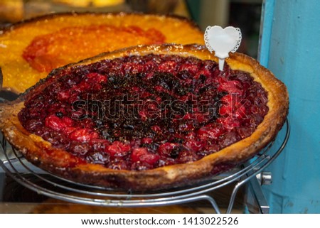 Delicious red fruit pie in a bakery window pane in Paris, France.
