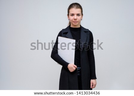 Photo portrait of a beautiful smiling brunette business woman with a folder on a white background in a black business suit with long beautiful dark hair in the studio. Right in front of the camera.