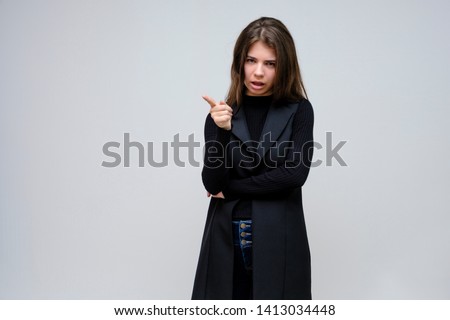 Photo portrait of a beautiful smiling brunette business woman on a white background in a black business suit with long beautiful dark hair in the studio. Standing right in front of the camera.