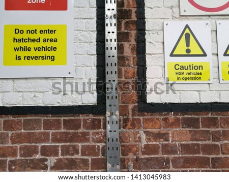 yellow warning signage on a brick wall with cable tray