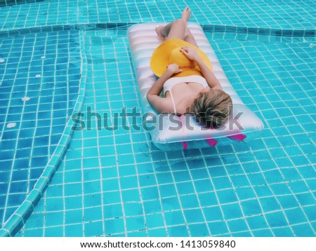 Beautiful Asian woman laying on pool floating in swimming pool.