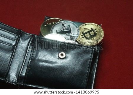 cryptocurrency coins in a black leather wallet on a velvet red background