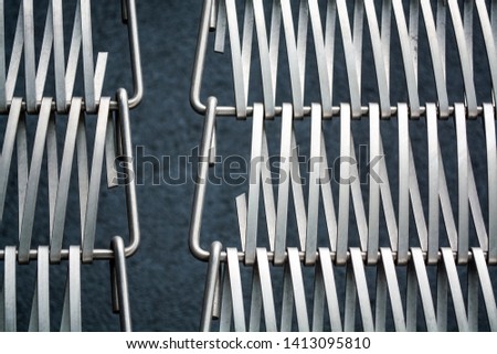Background or texture on a gray wall a lattice from metal a wire which intertwine among themselves. Hooks and loops. Geometry of lines.