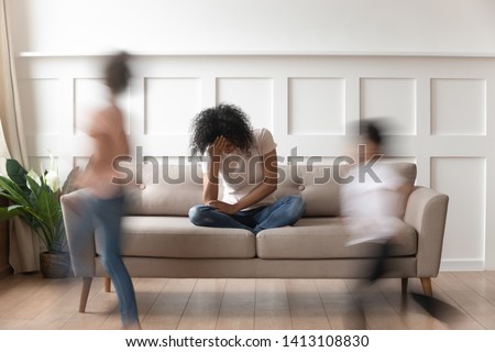 Frustrated stressed single african mom having headache feel tired annoyed about noisy active kids playing at home, upset disturbed black mother fatigued of difficult disobedient misbehaving children Royalty-Free Stock Photo #1413108830