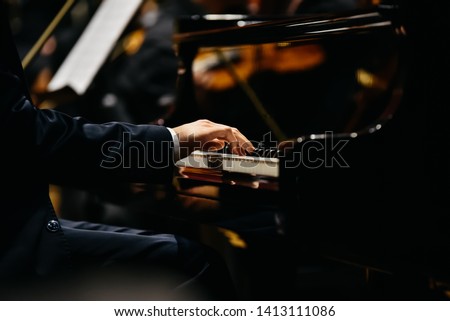 Pianist playing a piece on a grand piano at a concert, seen from the side. Royalty-Free Stock Photo #1413111086