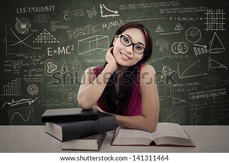Smiling friendly female college student with textbooks in classroom
