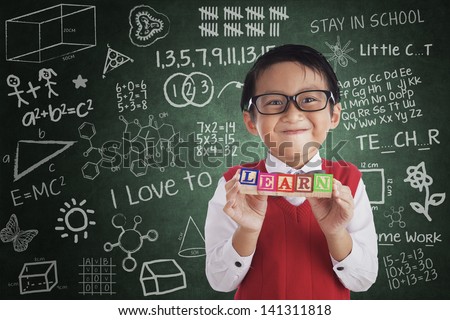 Boy smiling and holding LEARN crossword in class