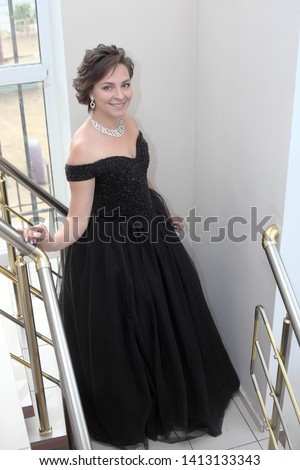 Young woman in a black dress on the stairs