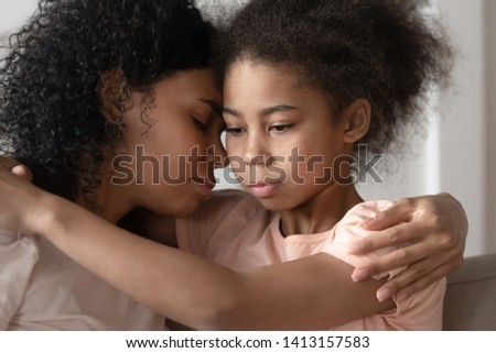 Thoughtful african american adopted kid daughter feeling sad embracing mom bonding cuddling, serious mixed race cute child daughter hugging black single mother foster parent giving love and comfort Royalty-Free Stock Photo #1413157583