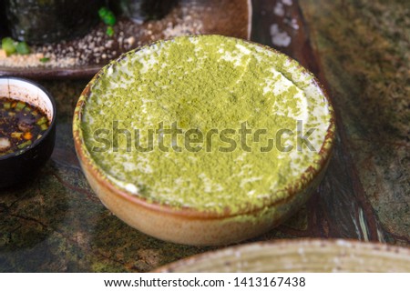 Dessert Tiramisu green tea, served in a small ceramic pot, presented on a marble table.