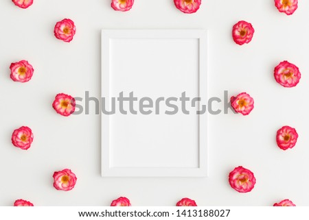 Top view of a white frame mockup with pink roses decoration on a white background.