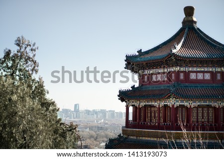 Traditional chinese pagoda in red blue and yellow, with a city as a background.