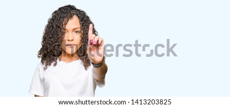 Young beautiful woman with curly hair wearing white t-shirt Pointing with finger up and angry expression