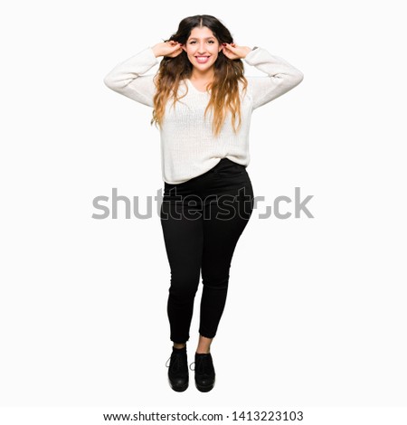 Young beautiful woman wearing white sweater Smiling pulling ears with fingers, funny gesture. Audition problem