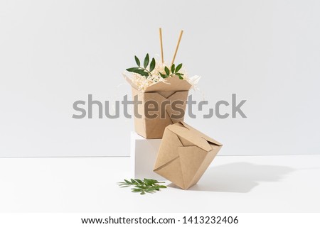 Disposable, compostable, recyclable paper hot food boxes with saw shawings and rowan branches in them over white background.
