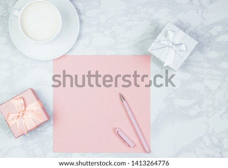Pink sheet of paper, pink pen, cup of coffee and gift boxes on the table. Pink blank card, sheet for writing. Layout for adding inscriptions. Top view, flat lay, copy space