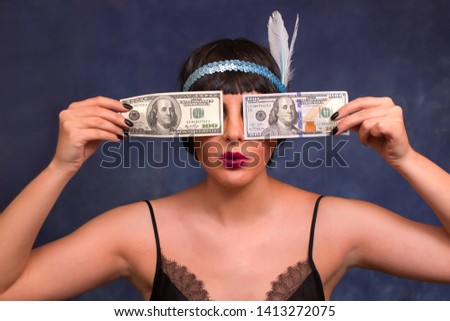 The woman closed her eyes with dollar bills. A woman holds in her hands $100 bills. Girl in retro image with dollars.