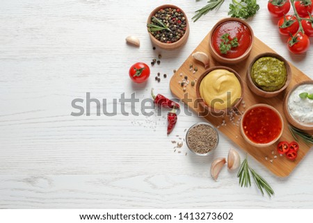 Flat lay composition with different sauces and space for text on white wooden background Royalty-Free Stock Photo #1413273602
