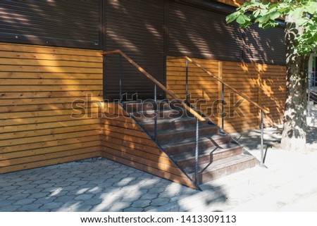 external entrance to the store from the street by stairs, steps with railings lead to the door of the outlet on the first floor of a residential building, a shopping district in a European city