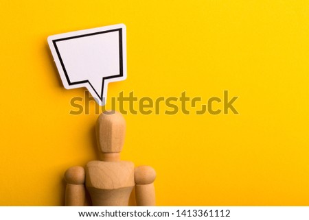 Thinking concept with blank speech bubble and wooden man on yellow background with copy space.