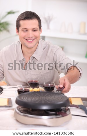Man enjoying raclette at home with friends